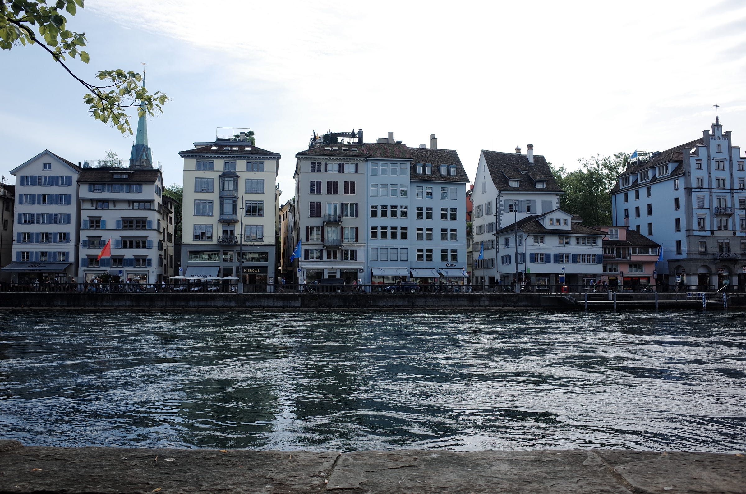 A photograph of the riverside in Zurich with buildings across the river
