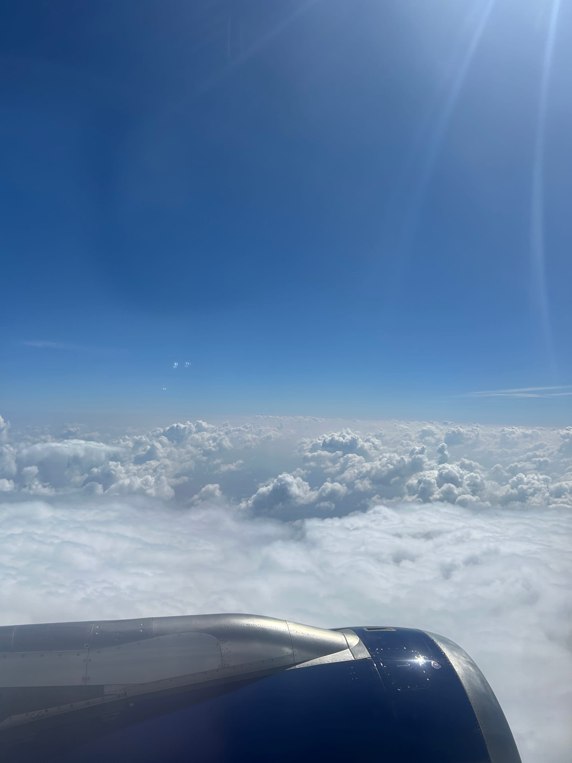 A photograph of some fluffy clouds taken from the airplane window