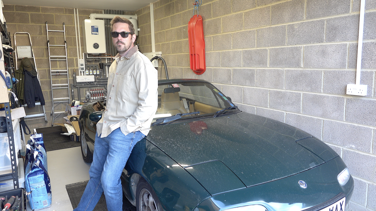 A photo of Rob Lambert next to his Mazda MX5 in his driving outfit