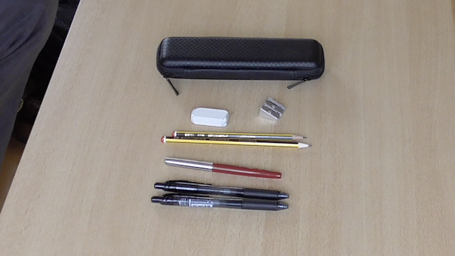 A photo of some pens next to a pencil case
